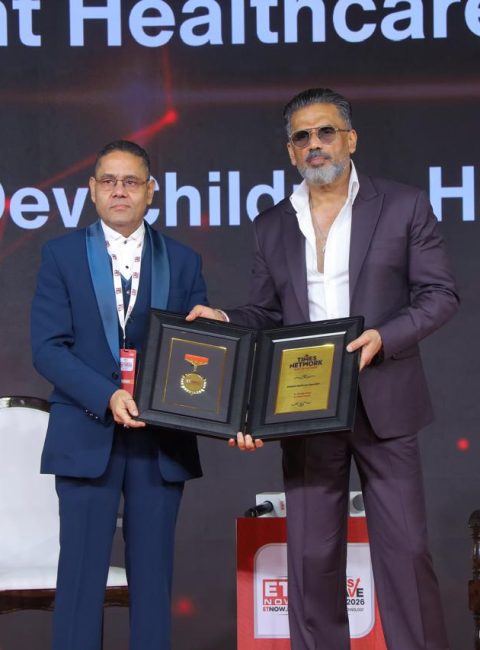 Award-winning pediatrician in Vadodara Dr. Anurag Singh holding national healthcare award on stage